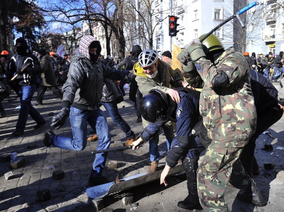 Varios manifestantes golpean a un policía. (Genya SAVILOV / AFP PHOTO)