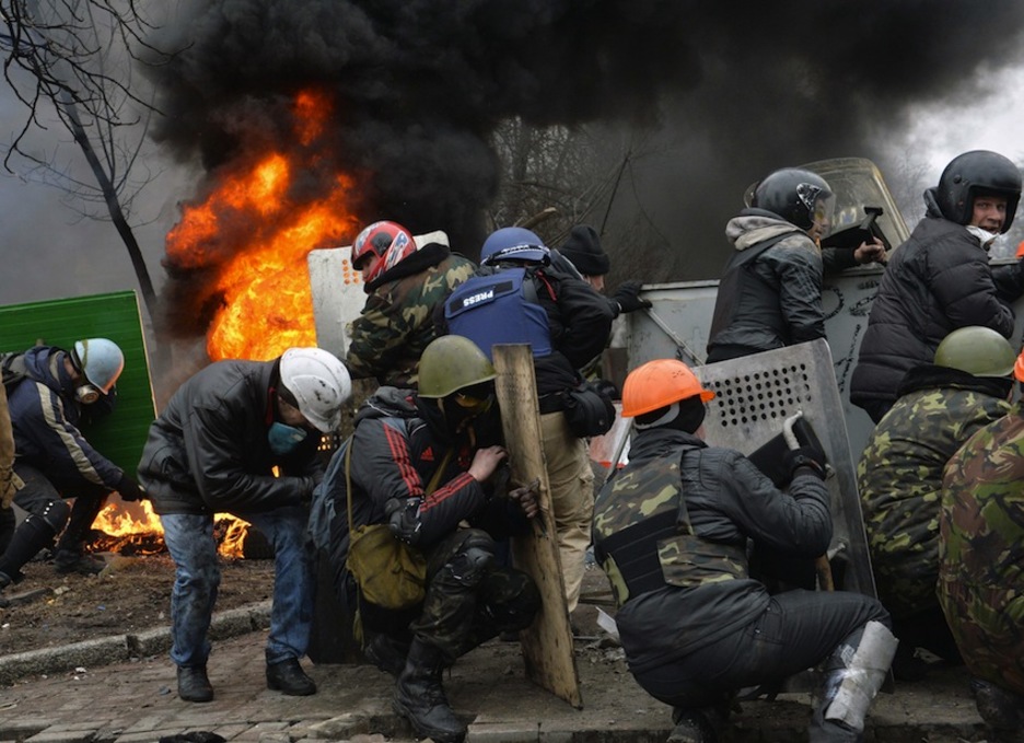 Los opositores se escudan frente a los ataques policiales. (Sergei SUPINSKY/AFP)