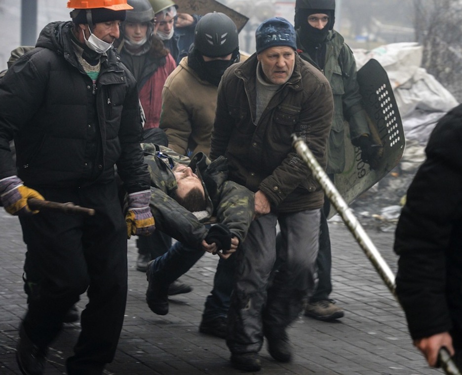 Opositores trasladan un hombre herido en los enfrentamientos. (Dmitry SEREBRYAKOV/AFP)