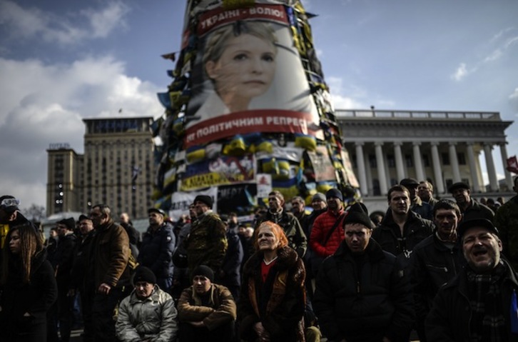 Manifestantes opositores siguen los acontecimientos bajo un retrato de Timoshenko. (Bulent KILIC / AFP PHOTO)