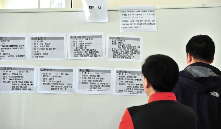 Dos personas miran información sobre los desaparecidos en el naufragio. (Jung YEON-JE/AFP) 