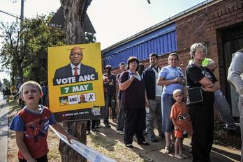 Fila de ciudadanos que atienden para votar ante un cartel que solicita el apoyo al ANC. (Stefan HEUNIS/AFP)