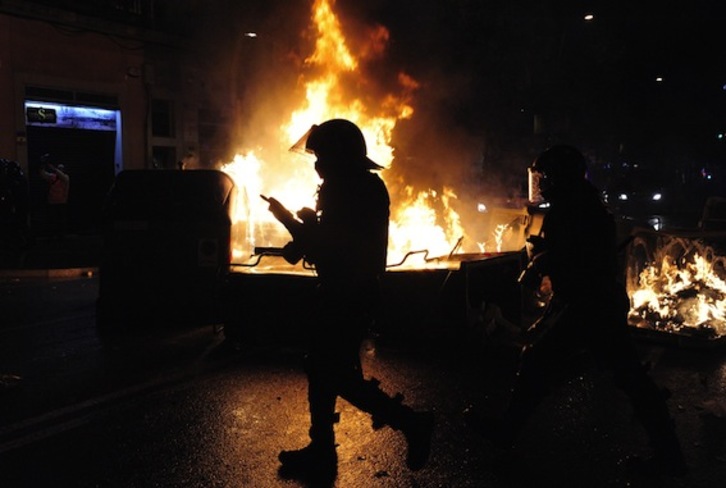 Un mosso frente a una barricada, ayer por la noche en el barrio de Sants. (Josep LAGO/AFP)
