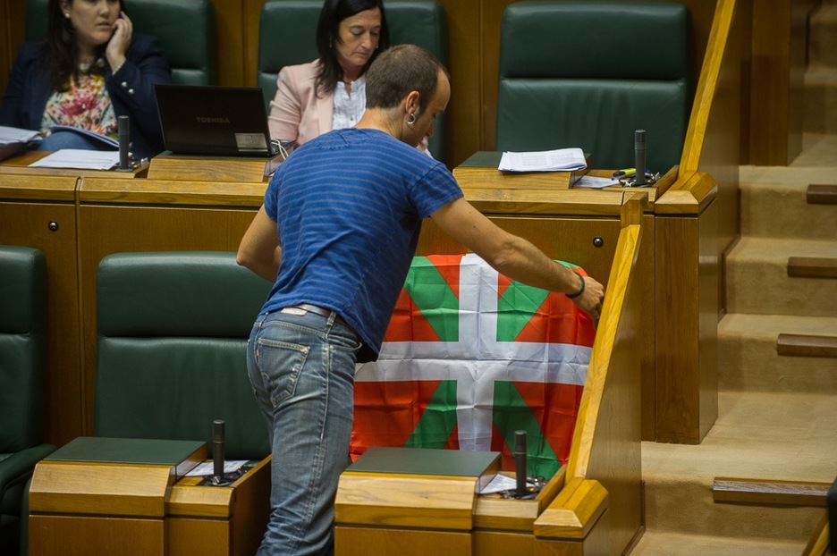 El parlamentario de EH Bildu Iñaki Lazarobaster coloca una ikurriña en el asiente del lehendakari, que estaba en Madrid para asistir a la coronación. (Juanan RUIZ / ARGAZKI PRESS) 