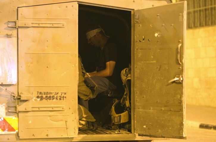 Uno de los arrestados, con los ojos vendados, en un furgón del Ejército israelí. (Hazem BADER/AFP)