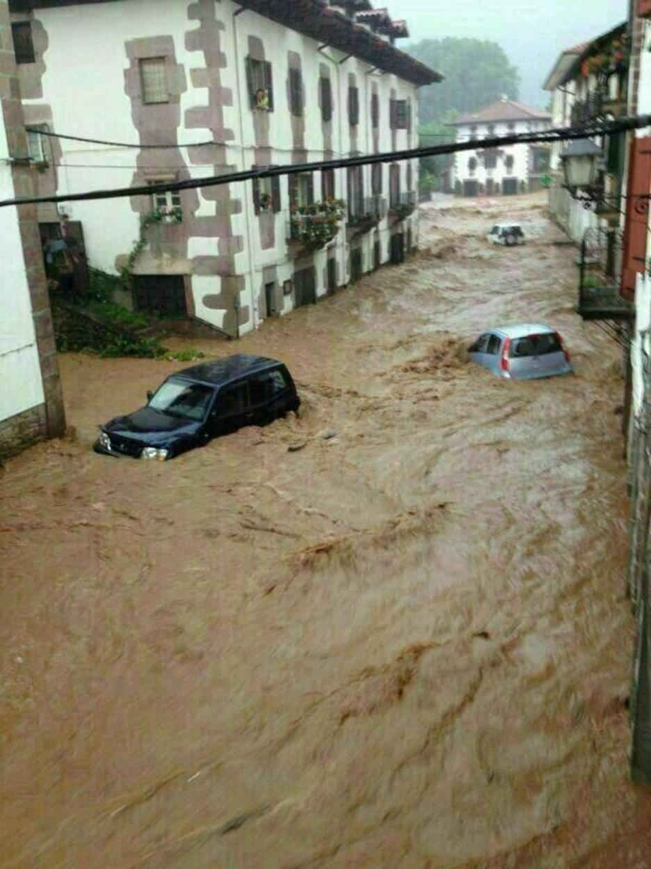 El agua arrastra los coches por una calle de Elizondo. (@OskarZabu)