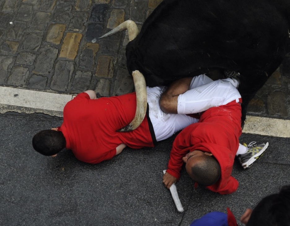 Dos mozos tratan de escapar bajo la cabeza del toro rezagado. (Jon URBE / ARGAZKI PRESS) Dos mozos tratan de escapar bajo la cabeza del toro rezagado. (Jon URBE / ARGAZKI PRESS)