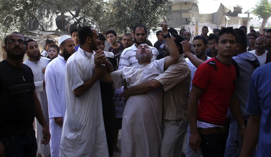 Varias personas consuelan a un vecino que ha visto su casa derribada por los bombardeos. (Thomas COEX/AFP)