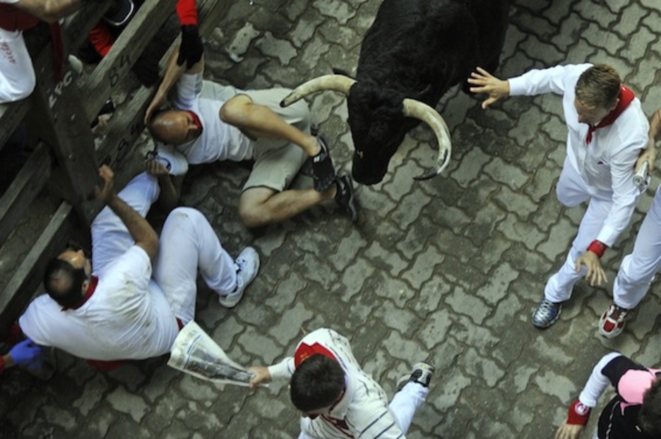 Dos corredores ven desde el suelo el paso de un astado. (Rafa RIVAS/AFP PHOTO)