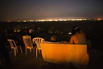 Vecinos de la localidad israelí de Sderot suben con sillas a una colina para ver los ataques sobre Gaza. (Menahem KAHANA/AFP PHOTO)
