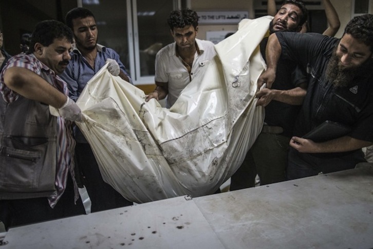 Voluntarios colocan un cuerpo sobre una mesa en el hospital de Shifa. (Marco LONGARI / AFP PHOTO) 