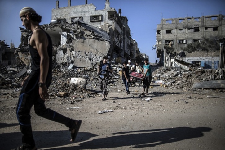 Unos palestinos trasladan objetos desde los escombros de sus viviendas destrozadas por los bombardeos en ciudad de Gaza. (Marco LONGARI/AFP) 
