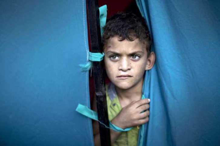 Un niño mira por detrás de las cortinas del hospital de Al-Shifa de Gaza. (Mahmud HAMS/AFP)