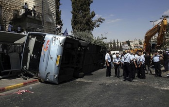La Policía israelí junto al autobús que ha quedado volcado en la carretera. (Ahmad GHARABLI/AFP)