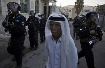 Un hombre palestino camina por Jerusalén rodeado de policías israelíes. (Ahmad GHARABLI / AFP) 
