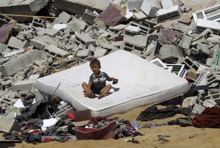 Un niño palestino, sentado en un colchón sobre los escombros de una casa destruida en Gaza. (Said KHATIB/AFP PHOTO)