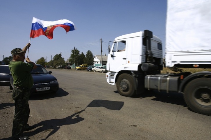 Un hombre ondea una bandera rusa al paso de los camiones en la localidad ucraniana de Izvarino. (Sergey VENYAVSKY /AFP)