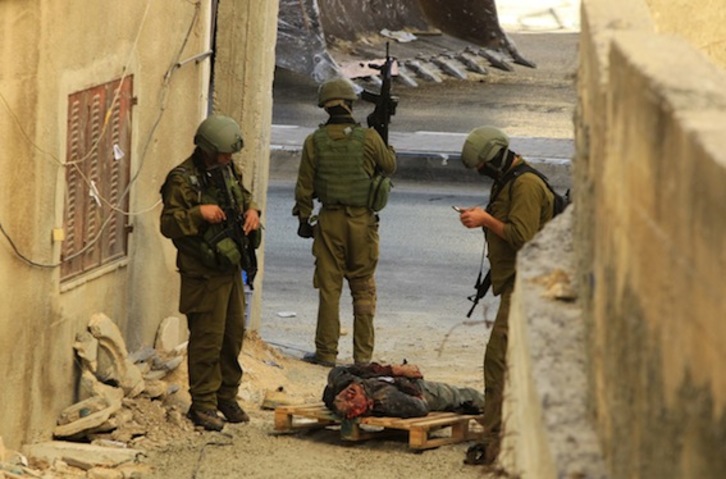 Soldados israelíes, junto al cadáver de uno de los palestinos muerto a tiros en Hebron. (Hazem BADER/AFP PHOTO)
