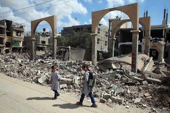 Dos niñas pasan ante un edificio destruido en el sur de Gaza. (Said KHATIB/AFP) 