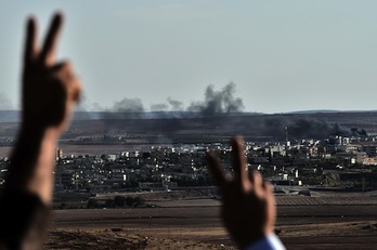 Dos personas hacen el gesto de la victoria ante el avance de los kurdos en Kobane. (Aris MESSINIS/AFP PHOTO)