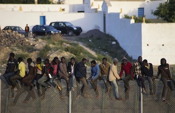 Inmigrantes encaramados este miércoles a la valla de Melilla. (Blasco AVELLANEDA / AFP)