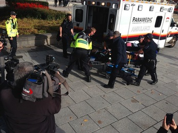 Policía y personal sanitario atienden al soldado herido en Ottawa. (Michel COMTE/AFP)