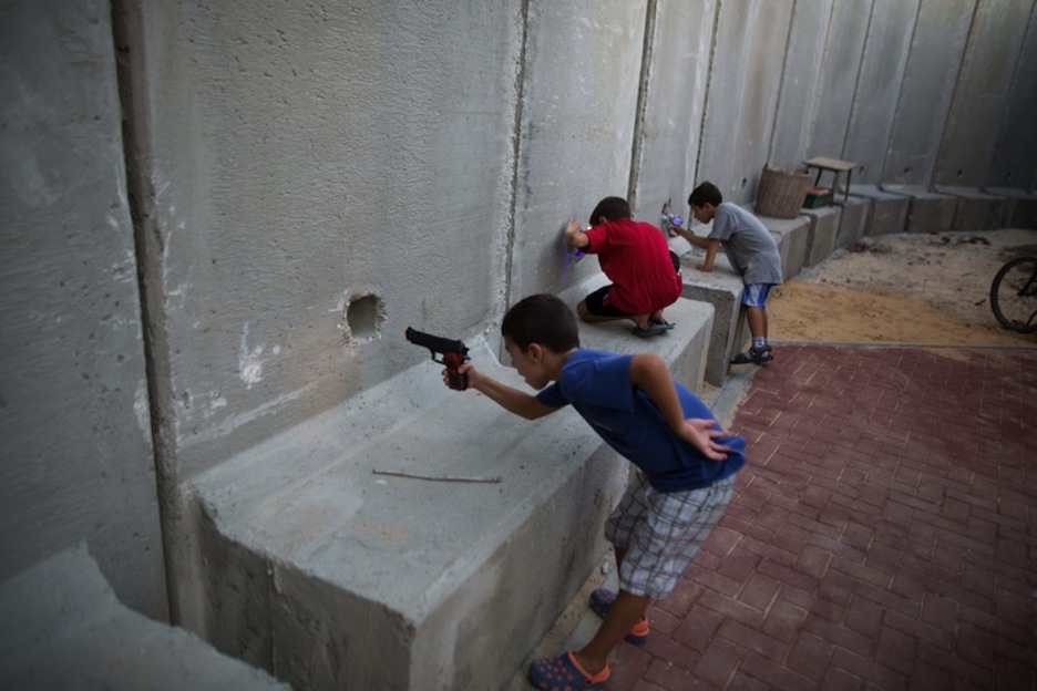 Israeldar haurrak harresiaren bestaldera tiro eginez jolasean, Gazan. (Menahem KAHANA / AFP) Israeldar haurrak harresiaren bestaldera tiro eginez jolasean, Gazan. (Menahem KAHANA / AFP)