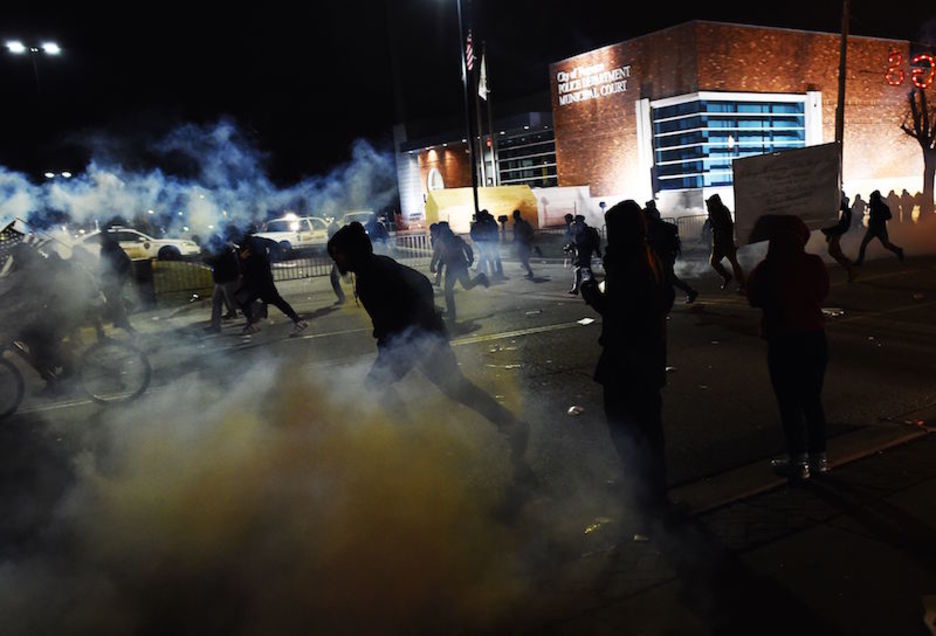 Jóvenes corren en Ferguson entre el gas lacrimógeno (JEWEL SAMAD / AFP). 