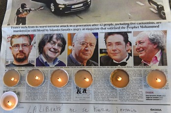 Velas sobre la portada de un diario en la que aparecen las caras de algunos de los dibujantes fallecidos en el ataque. (Anne-Christine POUJOULAT/AFP PHOTO)