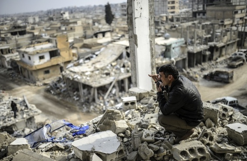 Un hombre habla por radio en lo alto de un edificio en Kobane. (Bulent KILIC/AFP PHOTO)