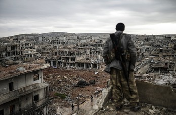 Un miliciano kurdo observa la destruida ciudad de Kobane. (Bulent KILIC/AFP)
