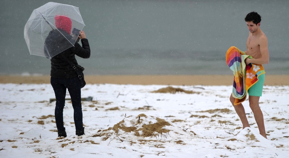 Elurra eta hotza ez dira oztopo Ondarretan bainu bat hartzeko. (Ander GILLENEA/AFP)