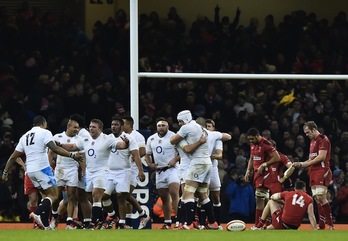 Ingleses exultantes junto a abatidos galeses al término del choque. (Ben STANSALL / AFP)