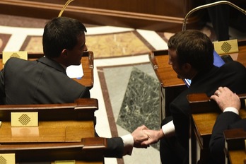 Valls se da la mano con el ministro Macron tras superar la votación. (Martin BUREAU / AFP)