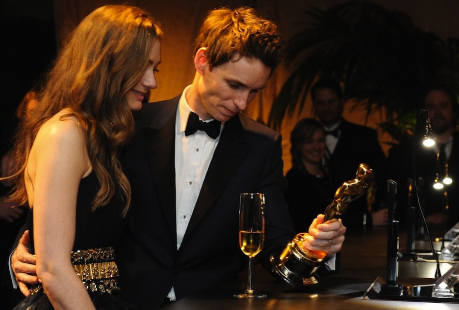 Eddie Redmayne, mejor actor por su interpretación de Stephen Hawking, contempla el trofeo junto a su pareja Hannah Bagshawe. (Valeria MACON / AFP)