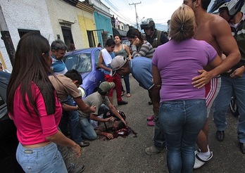 Un grupo de personas, alrededor del cuerpo del joven Kluivert Roa. (George CASTELLANO/AFP PHOTO)