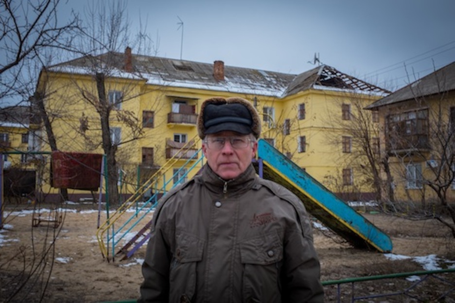 Yuri, habitante de Schastie, con el edificio donde vive y bombardeado según él (y la trayectoria los confirma) por las fuerzas ucranianas.