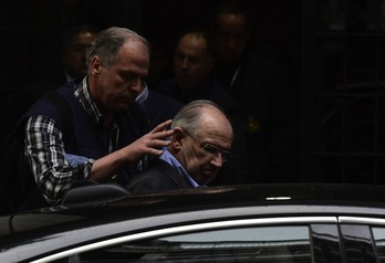 Rodrigo Rato es ayudado por un agente a entrar en el vehículo policial. (Javier SORIANO / AFP)