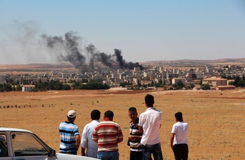 Un grupo de kurdos observa desde la frontera turca la columna de humo que emerge de Kobane. (AFP)