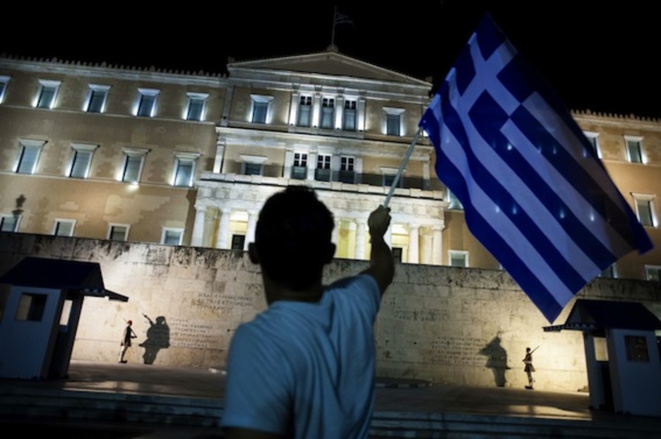 Un hombre agita una bandera griega frente al Parlamento. (Iakovos HATZISTAVROU/AFP PHOTO)