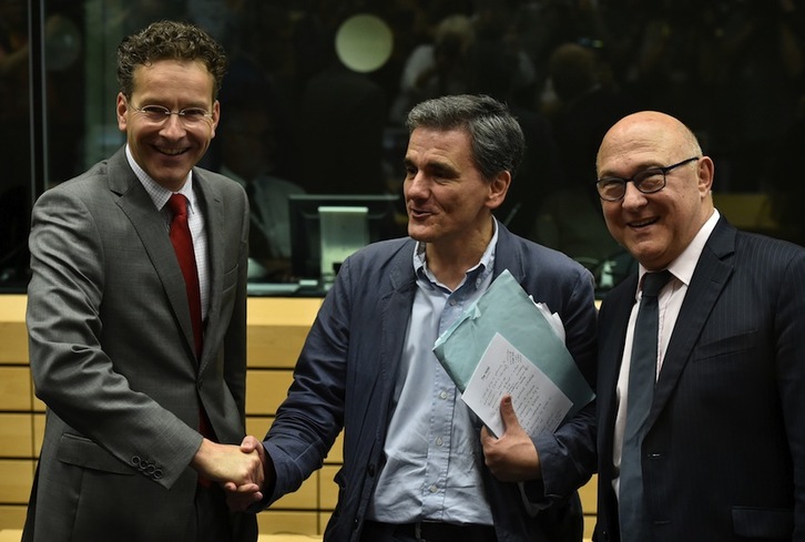 El presidente del Eurogrupo, Jeroen Dijsselbloem (izda), estrecha la mano del nuevo titular de Finanzas griego, Euclides Tsakalotos, ante su homólogo francés, Michel Sapin. (John THYS)