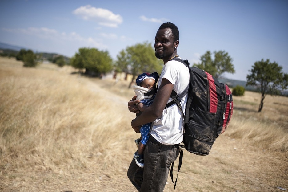 Un hombre con su hijo en brazos camina hacia Gevgelija. (Robert ATANASOVSKI/AFP) Un hombre con su hijo en brazos camina hacia Gevgelija. (Robert ATANASOVSKI/AFP)