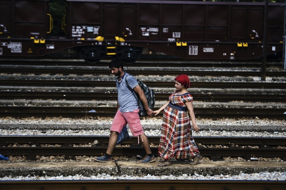 Una pareja camina por las vías del tren en Gevgelija. (Dimitar DILKOFF/AFP) 
