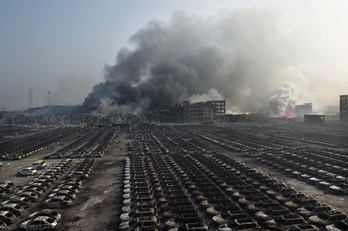 Una columna de humo se divisa tras una gran cantidad de vehículos calcinados. (Greg BAKER/AFP PHOTO)