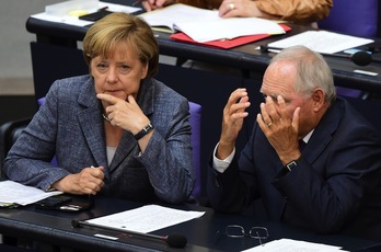 Angela Merkel habla con el ministro Wolfgang Schaeuble durante el debate de hoy. (John MACDOUGALL/AFP)