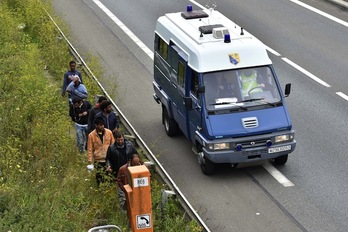 Un vehículo policial pasa al lado de unos inmigrantes cerca del Eurotúnel, en Calais. (Philippe HUGUEN/AFP)