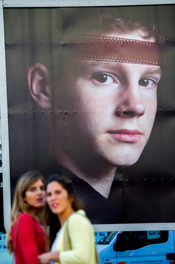 Zinemaldiko kartel bat eta jendea bertara gerturatzen