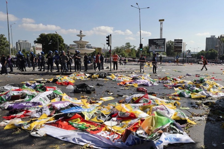 Policías observan los cadáveres de las víctimas cubiertos con banderolas y pancartas. (Adem ALTAN/AFP)