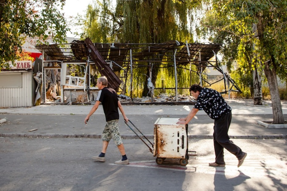 Dos hombres trasladan un frigorífico en el barrio de Oktyabrskii, cercano al aeropuerto de donetsk, completamente arrasado durante el conflicto. (Juan TEIXEIRA)