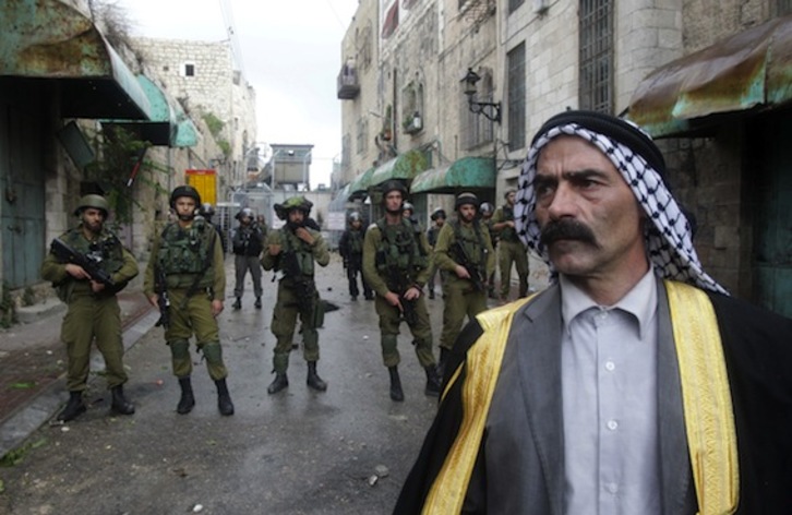 Un hombre pasa frente a un grupo de soldados israelíes en Hebrón, en la Cisjordania ocupada. (Hazem BADER/AFP PHOTO) 